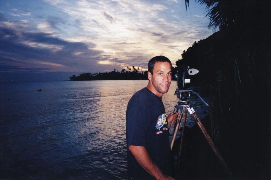 Jack Johnson beside a film camera on the coast at sunset